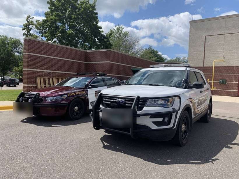 Minnesota State Trooper and sheriff's squad cars parked outside Talahi Elementary in St. Cloud, MN, during a community backpack giveaway