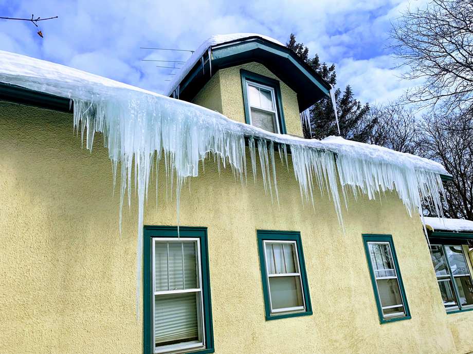 Wall of heavy icicles along the eave of a two-story stucco home