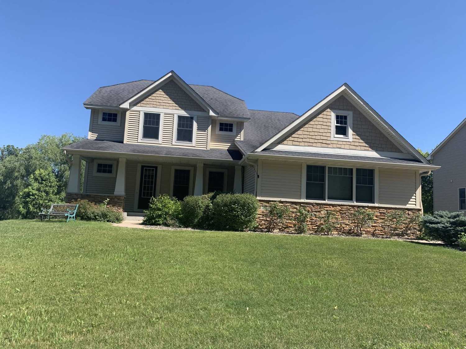 Two-story home with shake-style gables, a stone base and a covered front porch in Rockford, MN, photographed by Repair King during a July 2020 inspection
