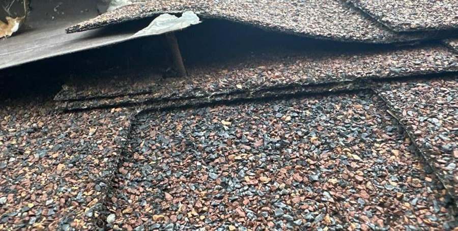 A creased, lifted shingle tab found during a Larson Court roof inspection in Shoreview, October 2023