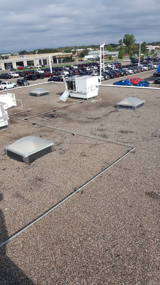 The dealership's old gravel-surfaced flat roof, with skylights and rooftop units, before Repair King replaced it