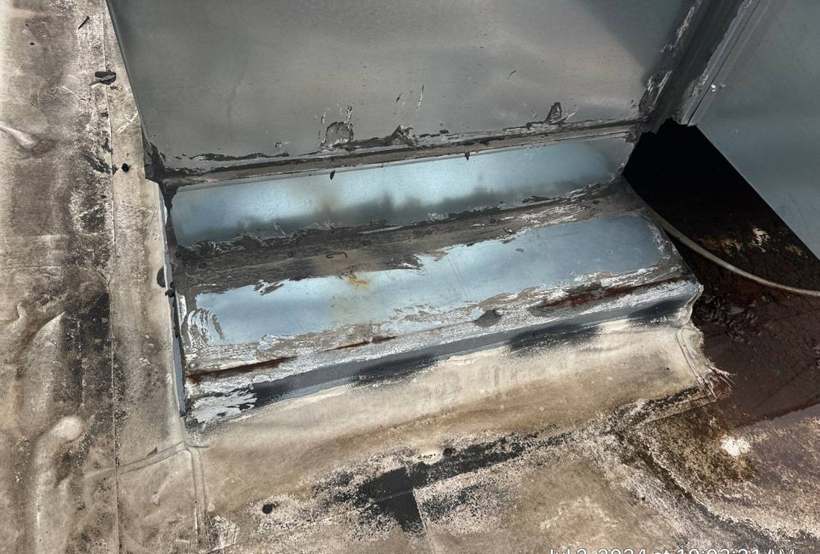 Worn and patched membrane at the base of a rooftop unit curb on the Bloomington Lincoln dealership roof in Bloomington, MN, July 2024