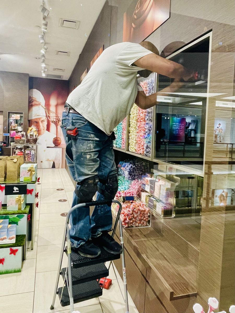 Repair King technician on a step ladder working on a retail display case door at Mall of America