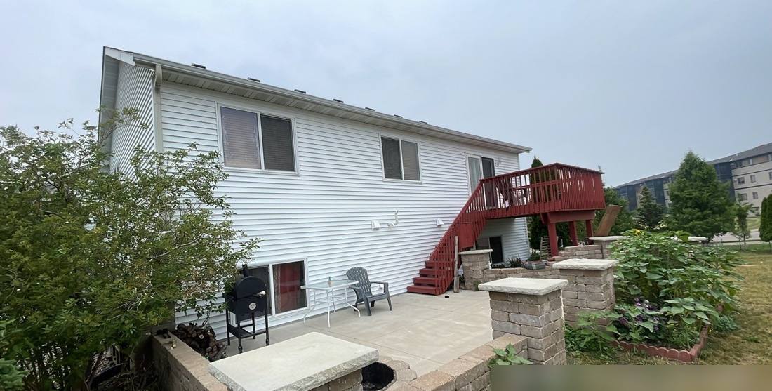 Back of a Sartell home with a patio and deck stairs, photographed during a roof inspection, June 2023