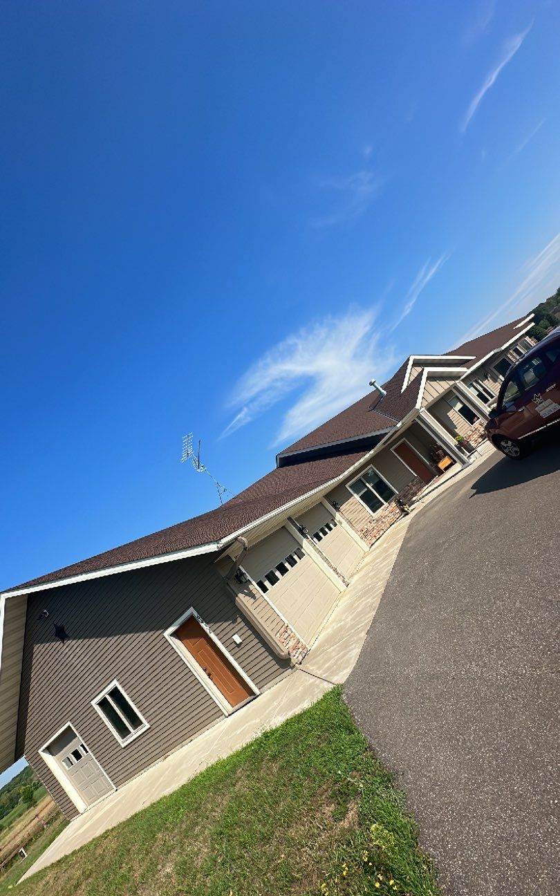 Wide exterior view of a home's roofline near Clearwater, MN under a clear blue sky, July 2023