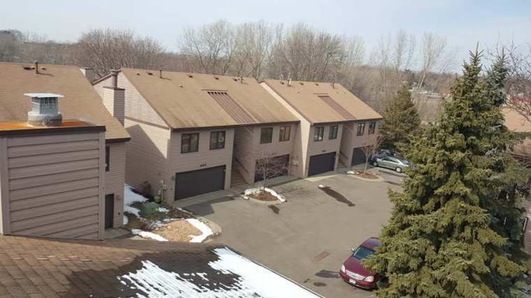 Row of brown two-story Maple Park Shores townhomes with attached garages, seen from the roof during a Repair King inspection in Maplewood, MN