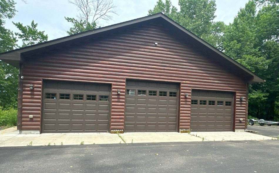 Three-car log-sided garage in Crosslake photographed during a roof inspection, June 2024