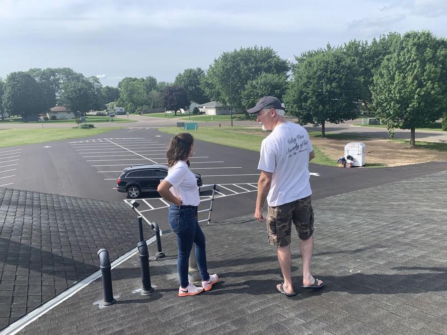 Pastor of Valley View Assembly of God and a Repair King team member on the church's new shingle roof in Lake City, MN, overlooking the freshly striped parking lot