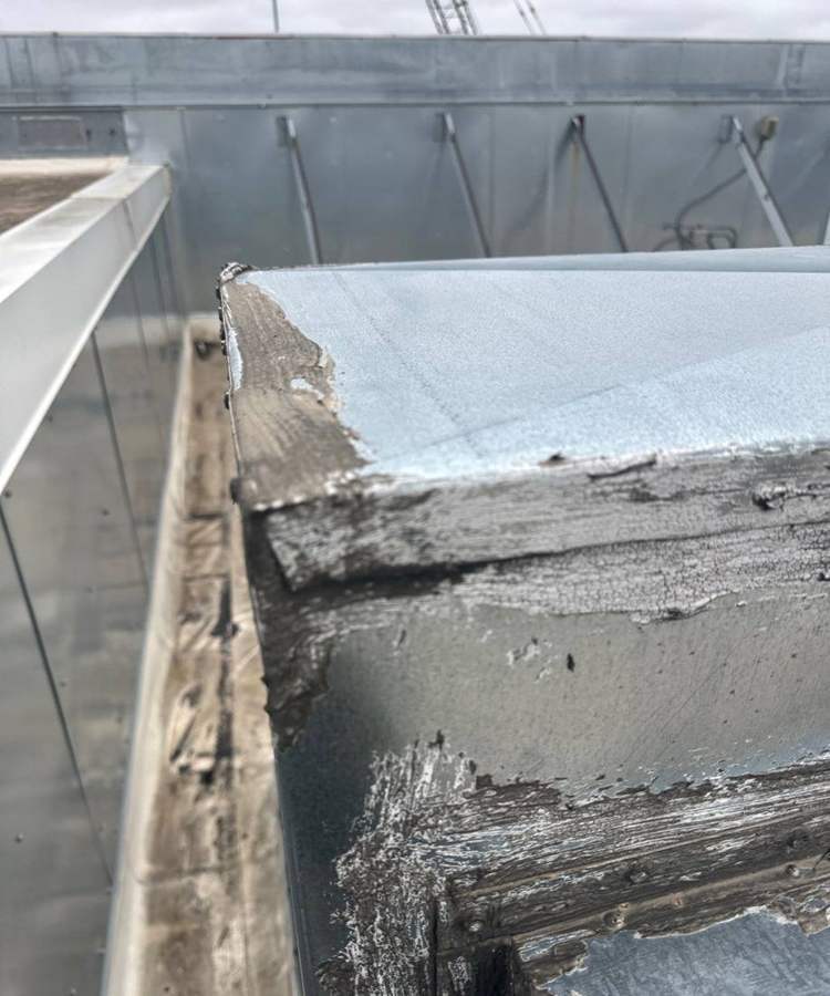 Deteriorated flashing at a rooftop curb beside the parapet on the Bloomington Lincoln roof, July 2024