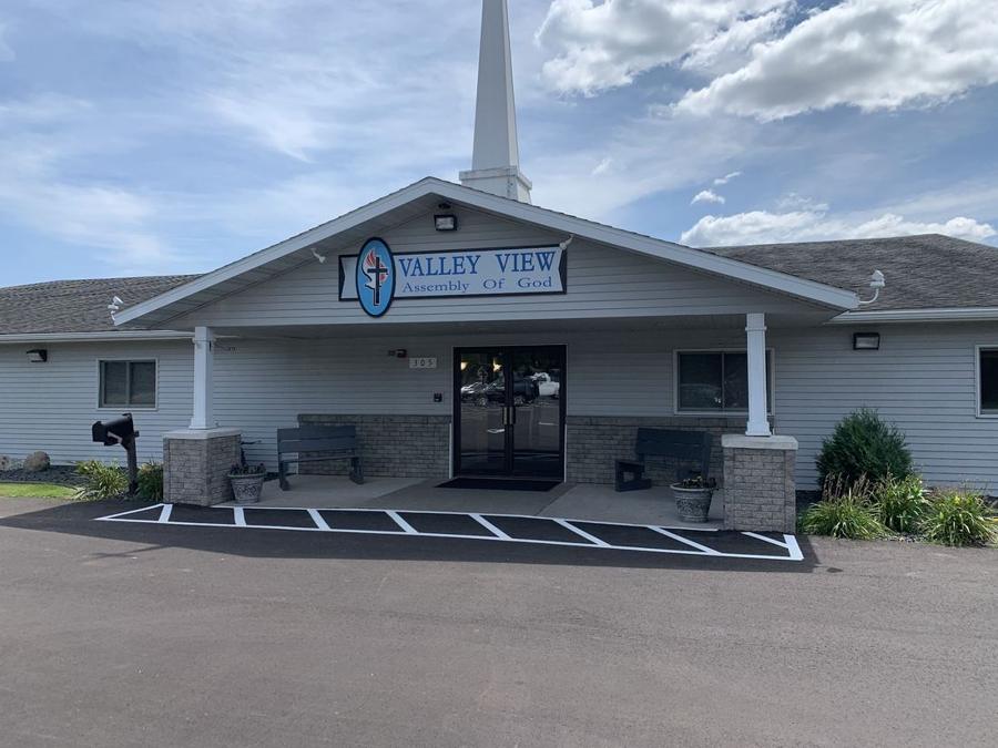 Front entrance of Valley View Assembly of God in Lake City, MN, with new siding, stone columns and a white steeple over the covered entry