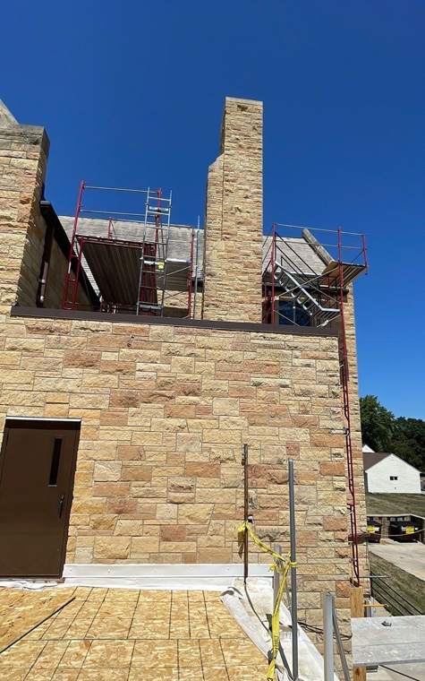 Scaffolding and guardrails around the stone chimney and upper walls of St. Paul's Lutheran Church in St. James, MN, during the July 2023 re-roof