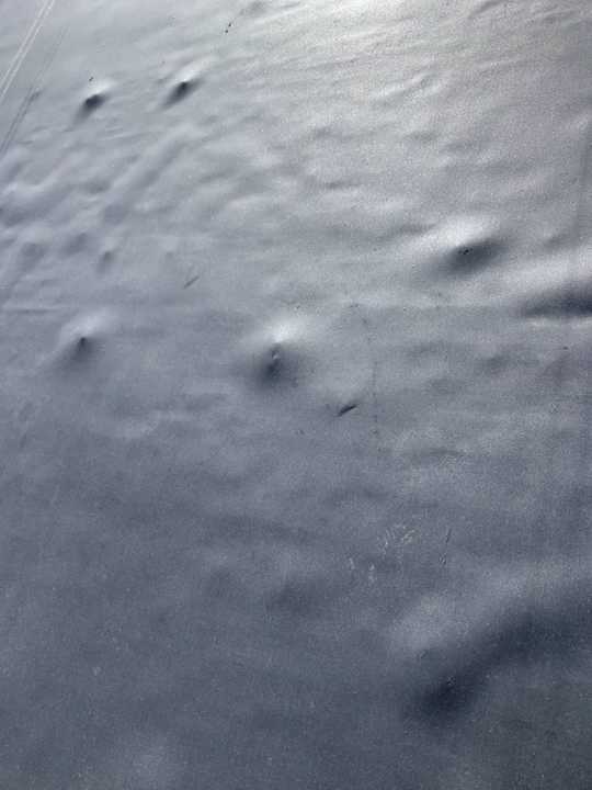 Round hail dents in the black rubber roof membrane at Paradise Car Wash in Maple Grove, MN, August 2019