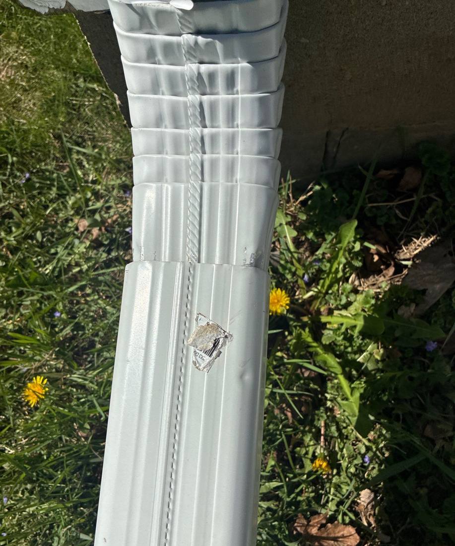 Dented aluminum downspout at a Red Wing home, April 2026