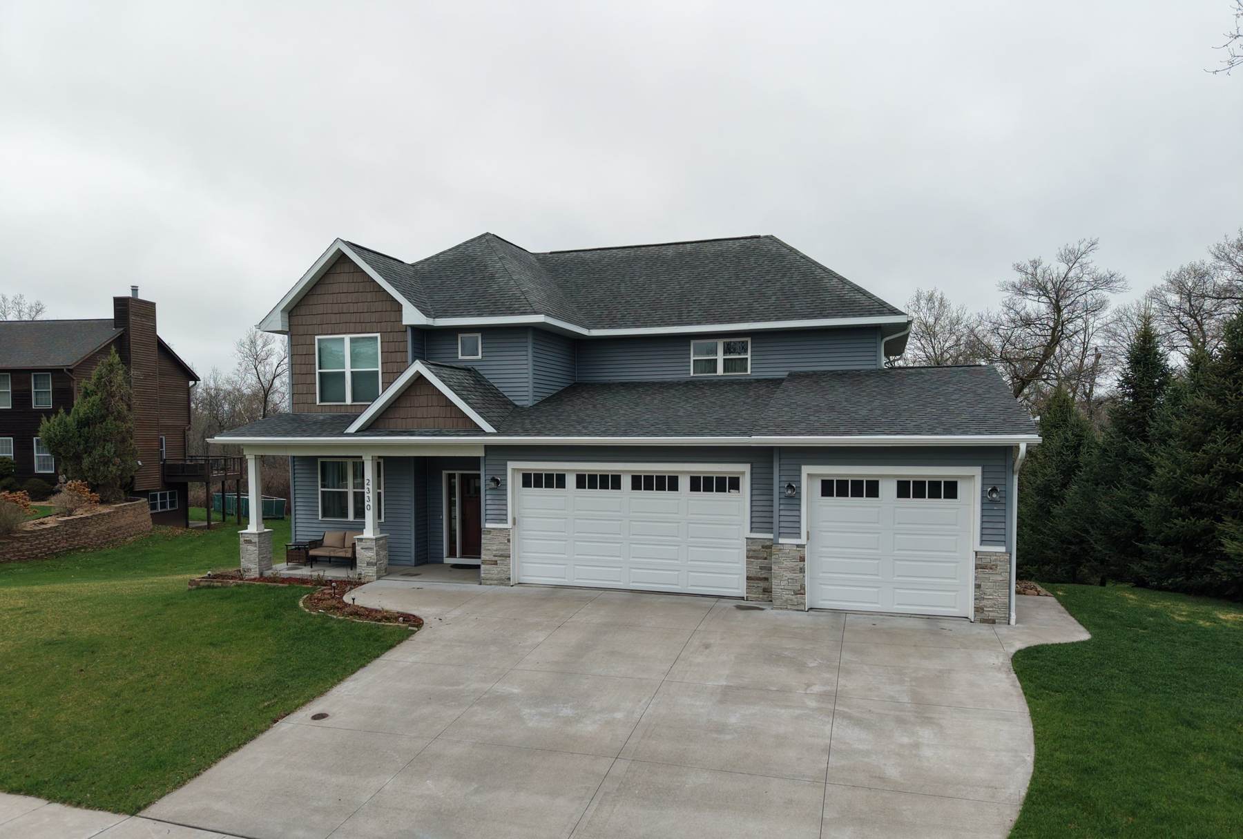 Two-story Red Wing, MN home with a gray architectural shingle roof, blue siding and a three-car garage, photographed during a Repair King roof inspection in April 2026