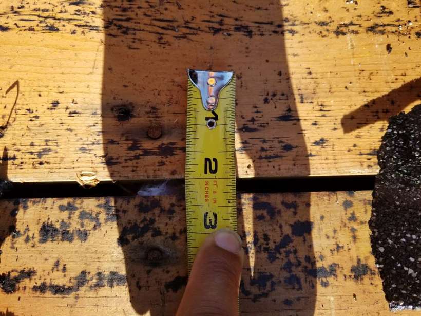 Tape measure across a gap between old plank deck boards after tear-off at Red Rock Lodge, Newport