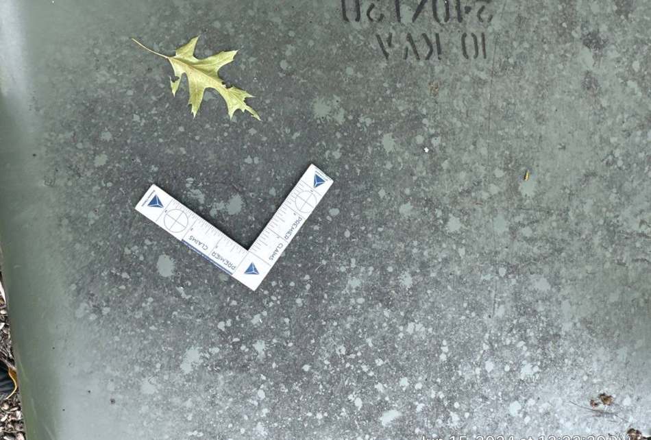 Hail dent measured with a claims scale on a Crosslake garage roof panel, June 2024