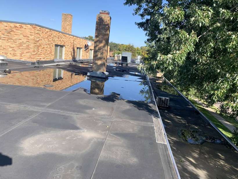 Standing water along a brick wall on the Washington Place flat roof in St. Cloud