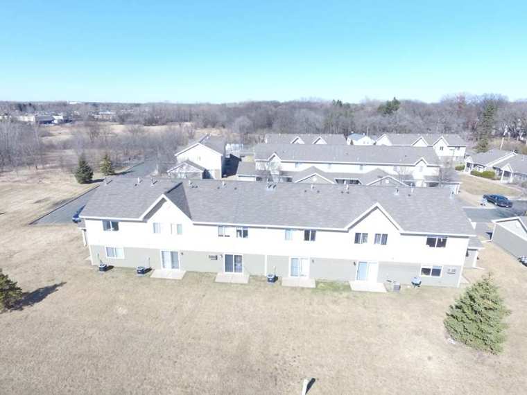 Drone view of a two-story white townhome building and its gray shingle roof in a Maplewood, MN townhome community during a Repair King inspection