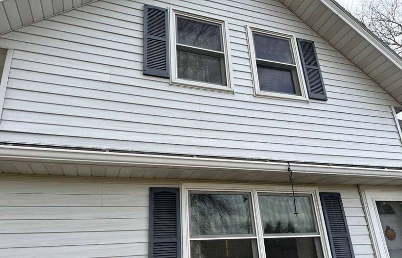 Upper-story white vinyl siding and windows on a farmhouse near Little Falls, MN, photographed during a January 2024 Repair King inspection