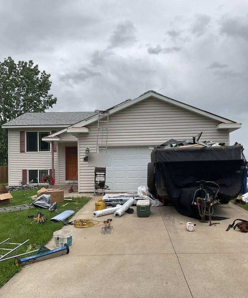 Materials staged in the driveway of a Dennison home during a full roof tear-off, June 2024