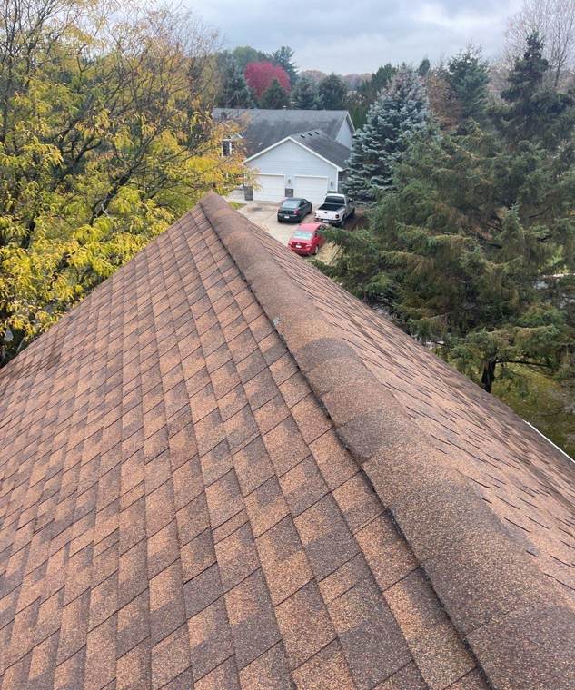 Ridge of a brown shingle roof above a wooded Wyoming neighborhood, October 2021