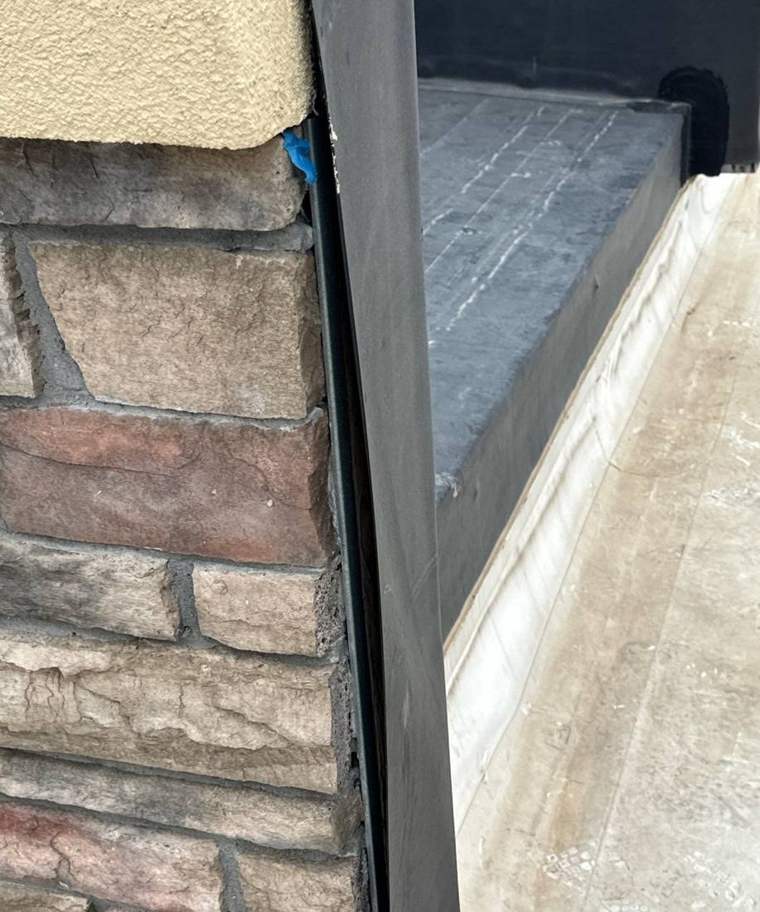 Membrane flashing where the Dairy Queen roof in Cokato meets its stone veneer and stucco wall, May 2024