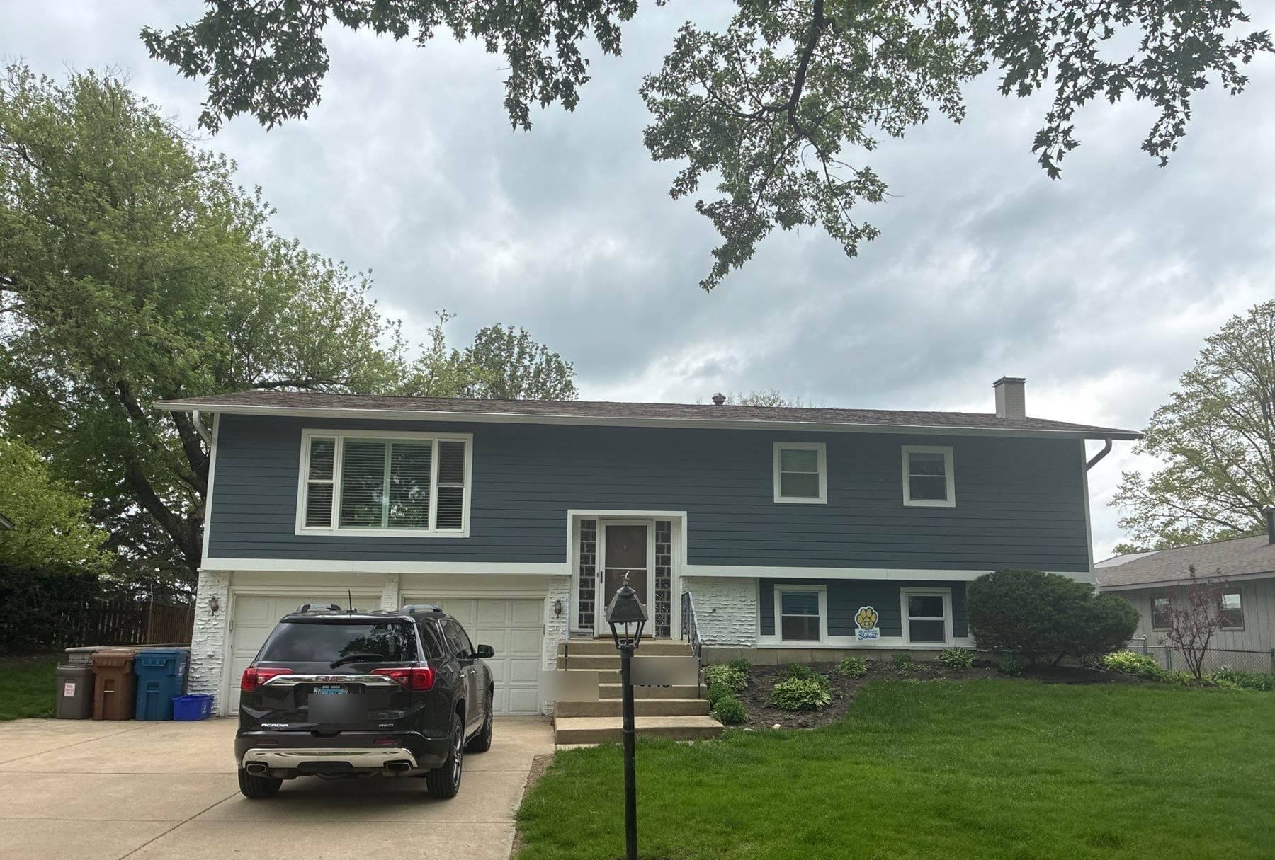 Split-level home in Downers Grove with new dark siding, freshly installed roof and GMC SUV in the driveway, April 2026