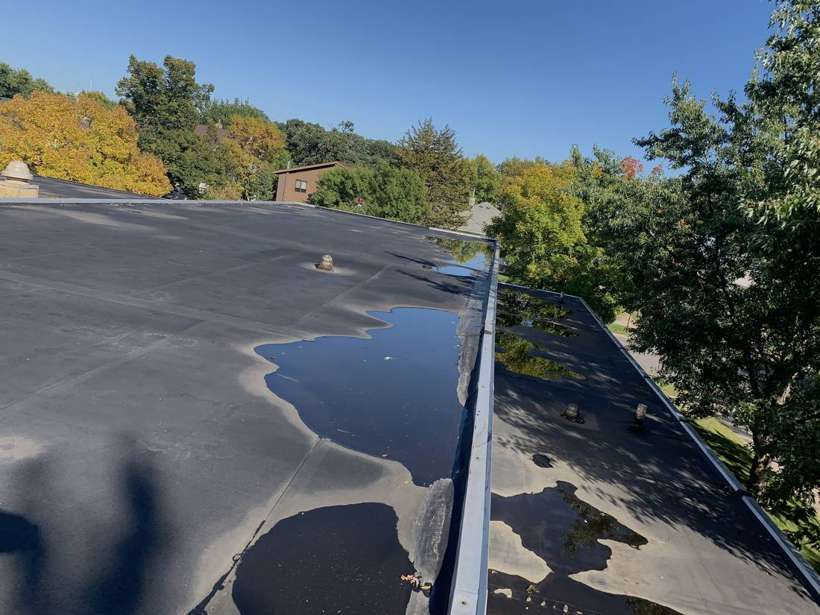 Ponded water on the black rubber flat roof of Washington Place in St. Cloud, MN, near Waite Park, during a Repair King inspection
