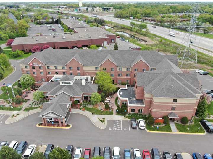 Drone view of the Hilton Garden Inn in Maple Grove, MN from the parking lot side, with I-494 and the power line corridor behind it