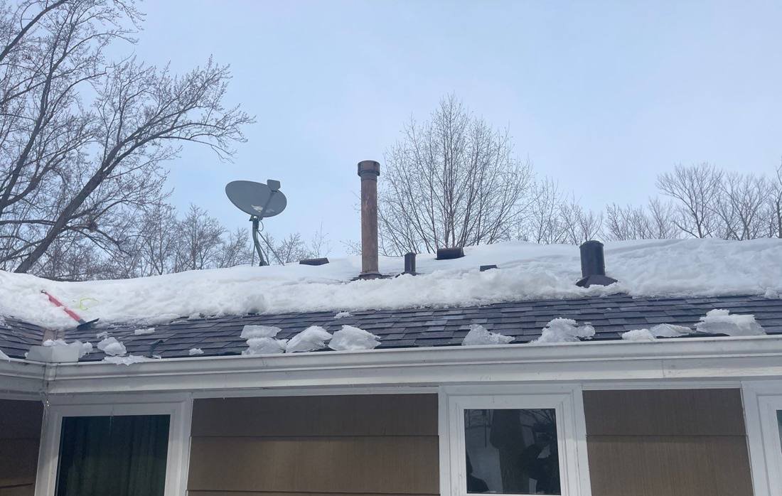 Snow load and ice buildup along the eaves of a Bloomington home, photographed during a January 2023 inspection
