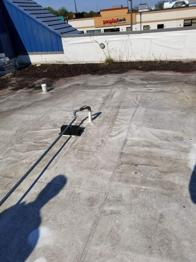 Roof membrane and a pipe penetration on the Good Earth roof, with Highway 36 businesses behind