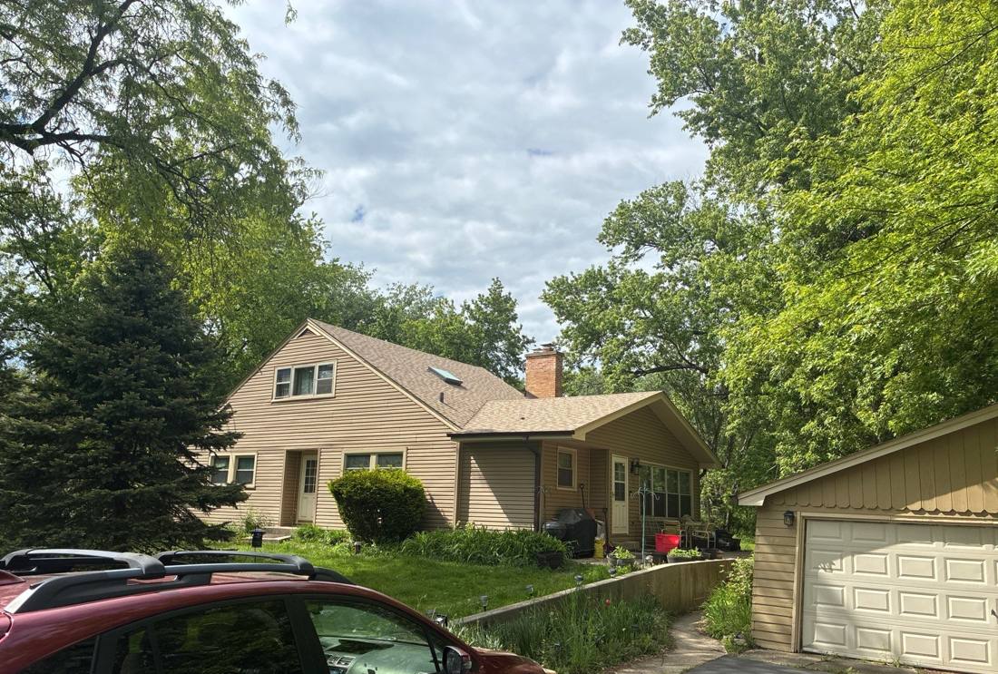 Home tucked among mature trees in Downers Grove, photographed during a roof project, May 2026