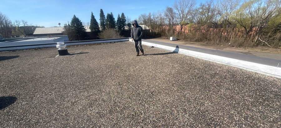 Walking the gravel-ballasted roof at Safe Reflections on Greeley Street South, April 2026