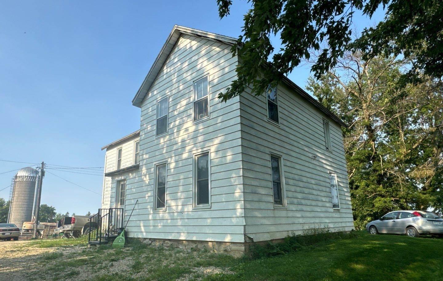Two-story farmhouse and grain silo on a Goodhue-area farm photographed by Repair King during a roof inspection, August 2024