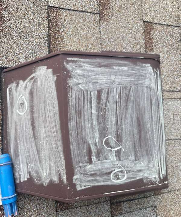 Chalk-rubbed metal box vent showing three hail dents on a Maplewood, MN roof, July 2025