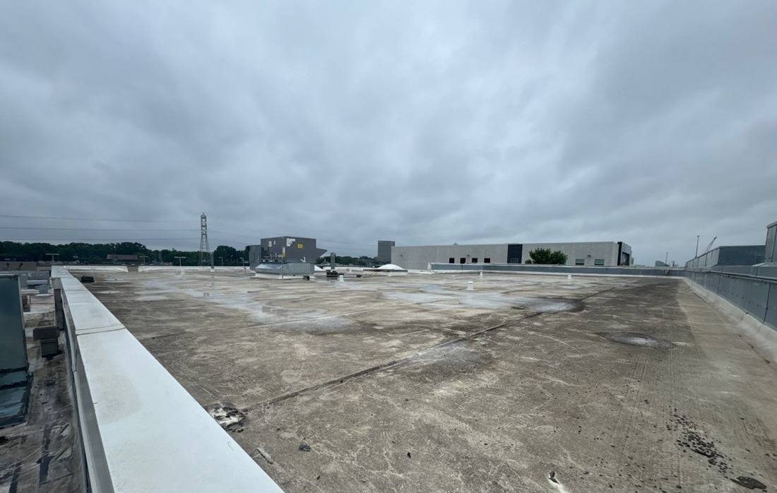 Long run of the Bloomington Lincoln flat roof with ponding stains along the parapet, photographed during our July 2024 inspection