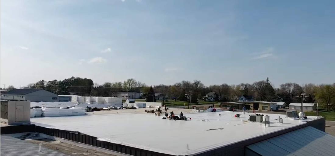 Repair King crew working across the low-slope roof of The Marketplace grocery store in Cokato