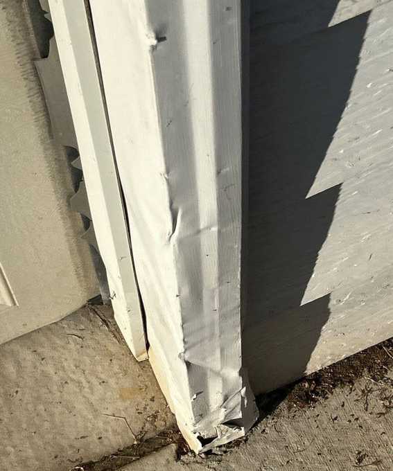 Bent, crumpled aluminum trim at the base of a garage door frame on 4th Avenue, Newport, September 2025