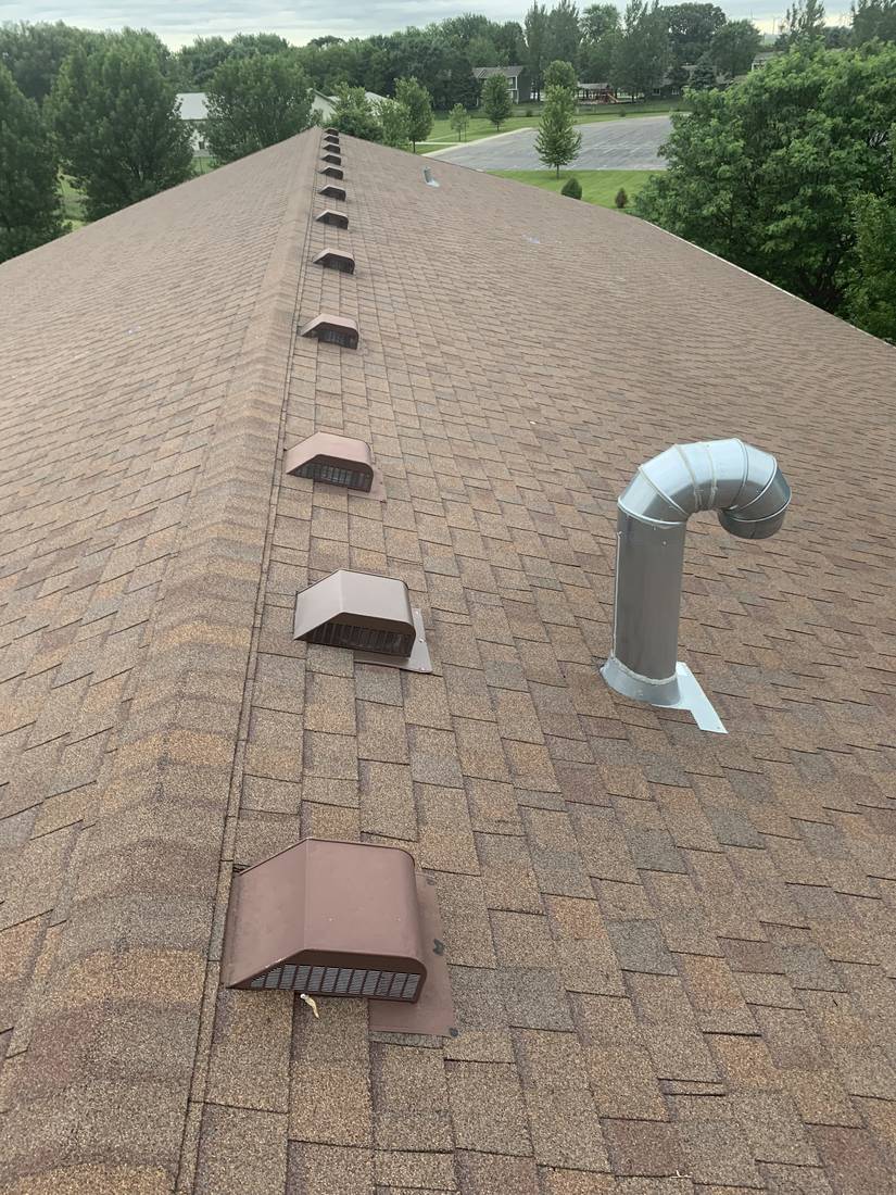 Row of brown box vents along the ridge and a metal exhaust stack on the Heritage Estates roof in Dodge Center, MN