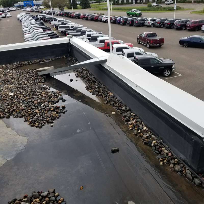 Ponding water along the parapet of the old gravel roof at Forest Lake Chrysler Jeep Dodge in Forest Lake, before Repair King replaced it