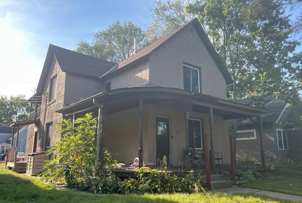 Two-story home near downtown St. Cloud with a wraparound porch, photographed during a roof project, September 2025