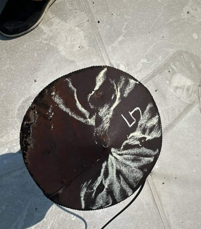 Hail spatter marks chalked on a dark round metal cover on the 106 South Main Street roof