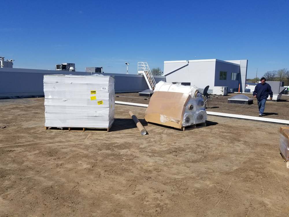 Crated rooftop equipment staged on the stripped flat roof of Forest Lake Chrysler Jeep Dodge in Forest Lake, MN during Repair King's roof replacement