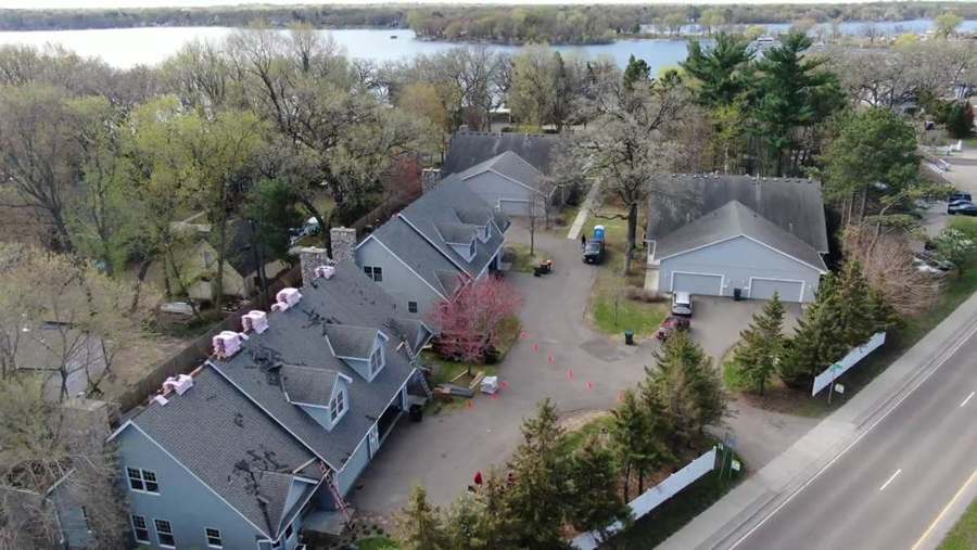 Drone view looking down a row of attached townhomes with shingle bundles on the roof during a Repair King re-roof in White Bear Lake, MN