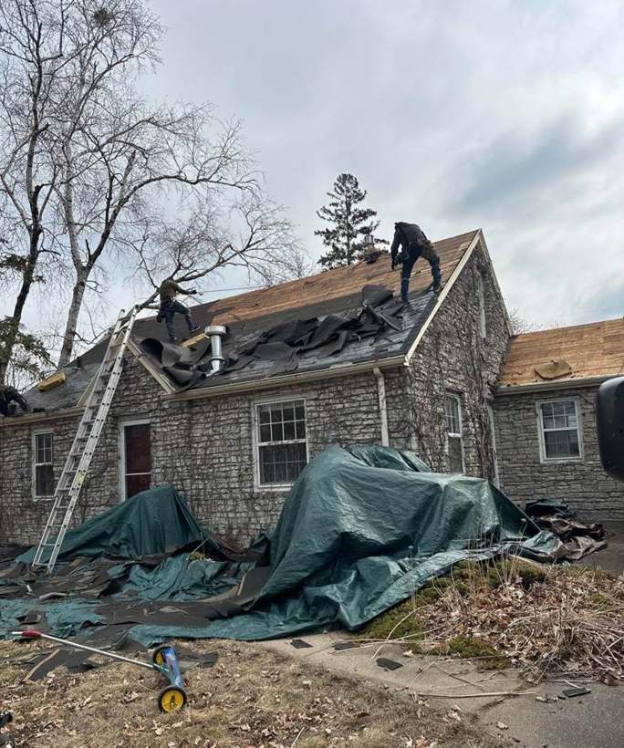 Tear-off underway on the stone-faced Richfield home, with tarps down to protect the yard, April 2025
