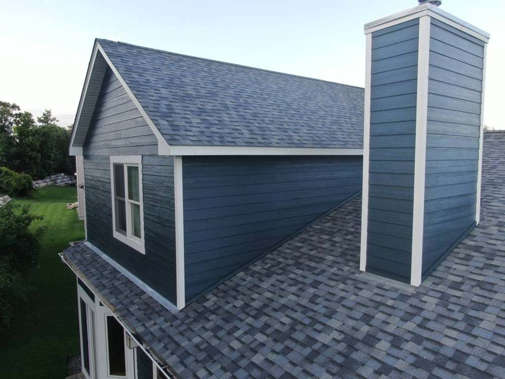 New blue lap siding on the chimney chase and a new shingle roof on a Ramsey home, August 2019