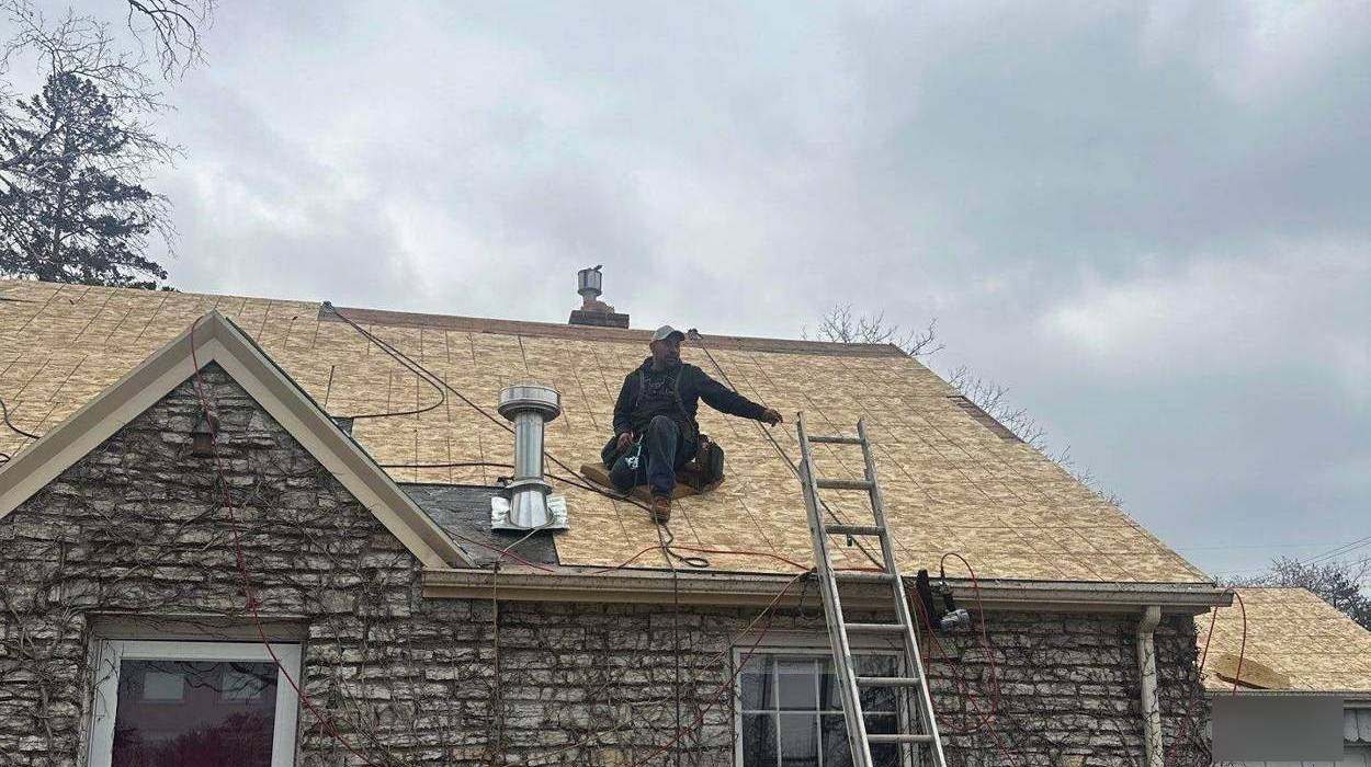 Repair King roofer installing new roof sheathing on a stone-faced story-and-a-half home in Richfield, MN, April 2025
