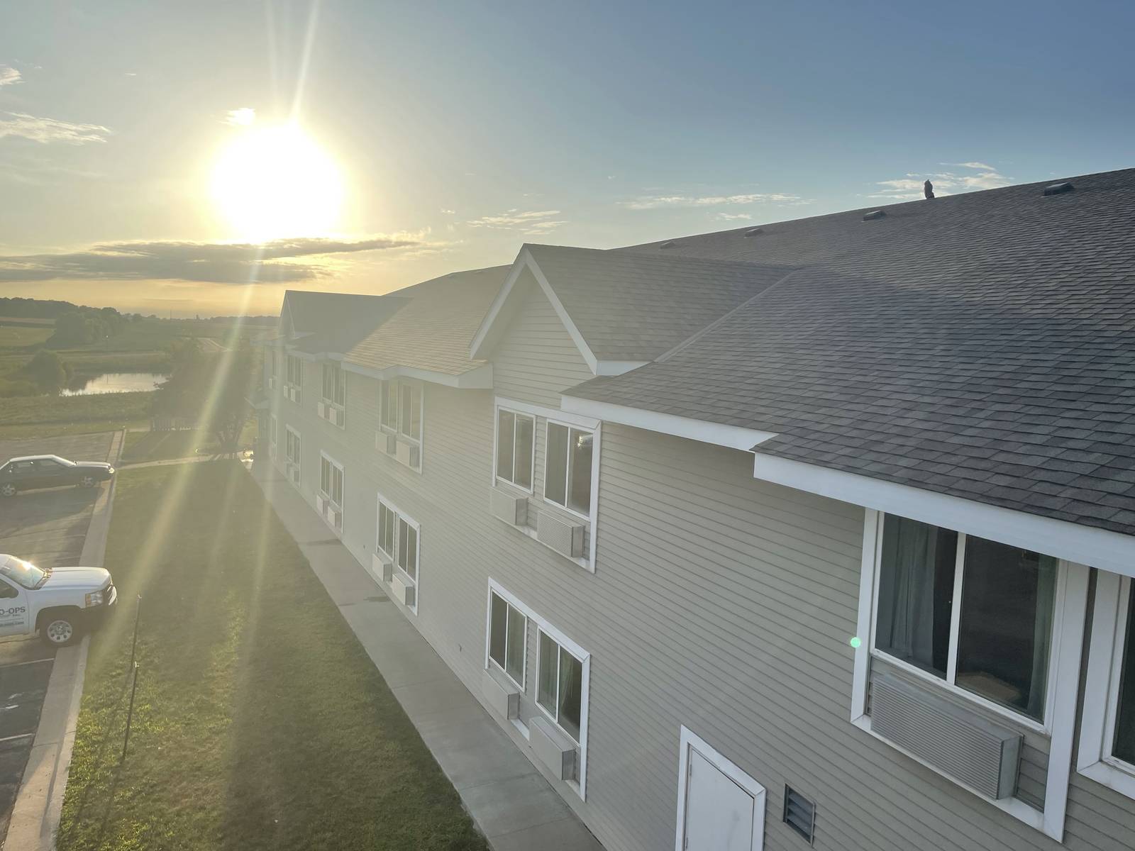 Evening sun over the shingle roof and vinyl lap siding of the GrandStay Hotel & Suites in Waseca, MN, seen from the roof during a Repair King inspection