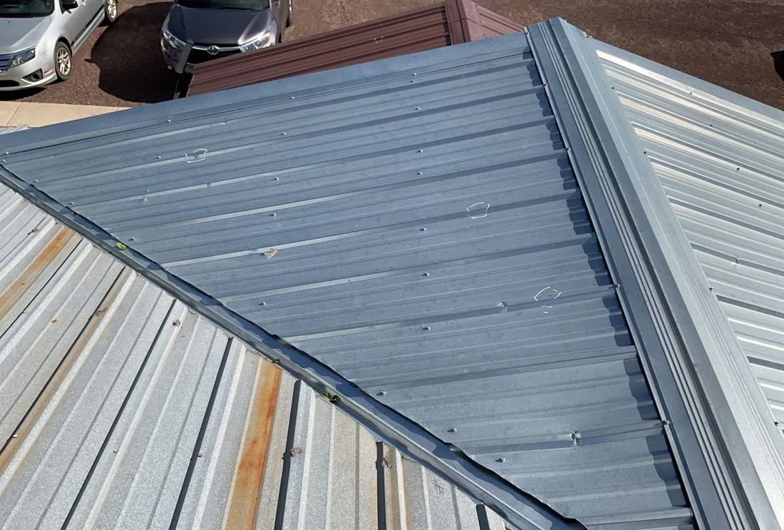 Hail dents circled on a standing-seam metal roof valley in Sandstone, June 2024