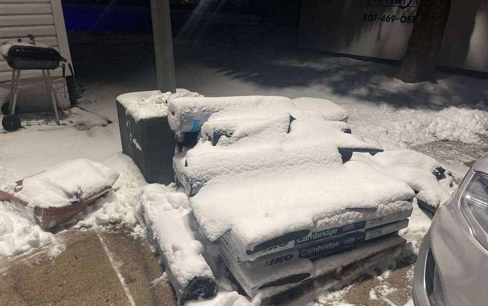 Snow-covered bundles of shingles staged at the Super 8 in Owatonna, MN, November 2022